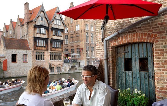 Two people having diner on a terrace near the water in Bruges, Belgium